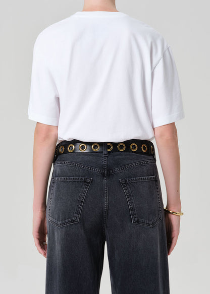 Person wearing a white t-shirt and black jeans with a belt on a plain background