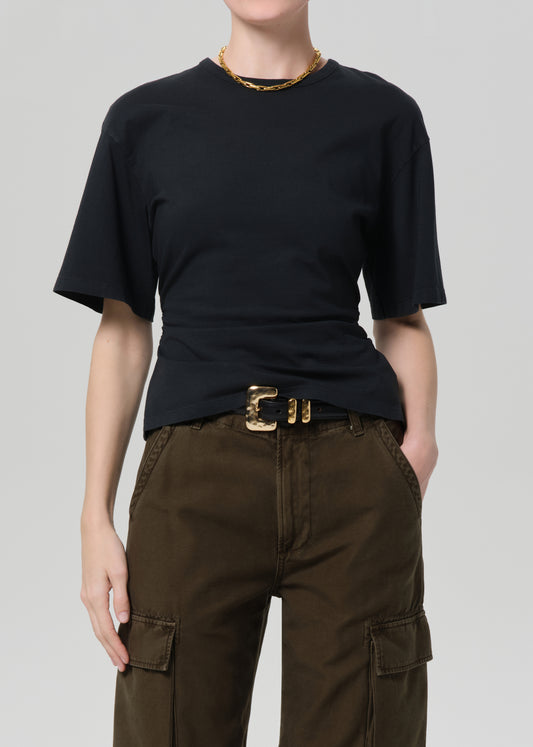 Person wearing a black t-shirt and brown cargo pants on a plain background