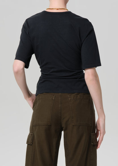 Person wearing a black t-shirt and brown cargo pants on a plain background