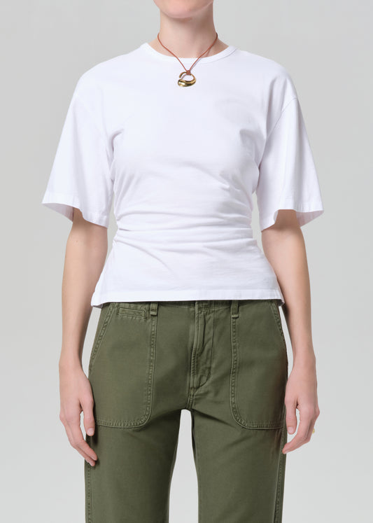 Person wearing a white t-shirt and green pants on a plain background