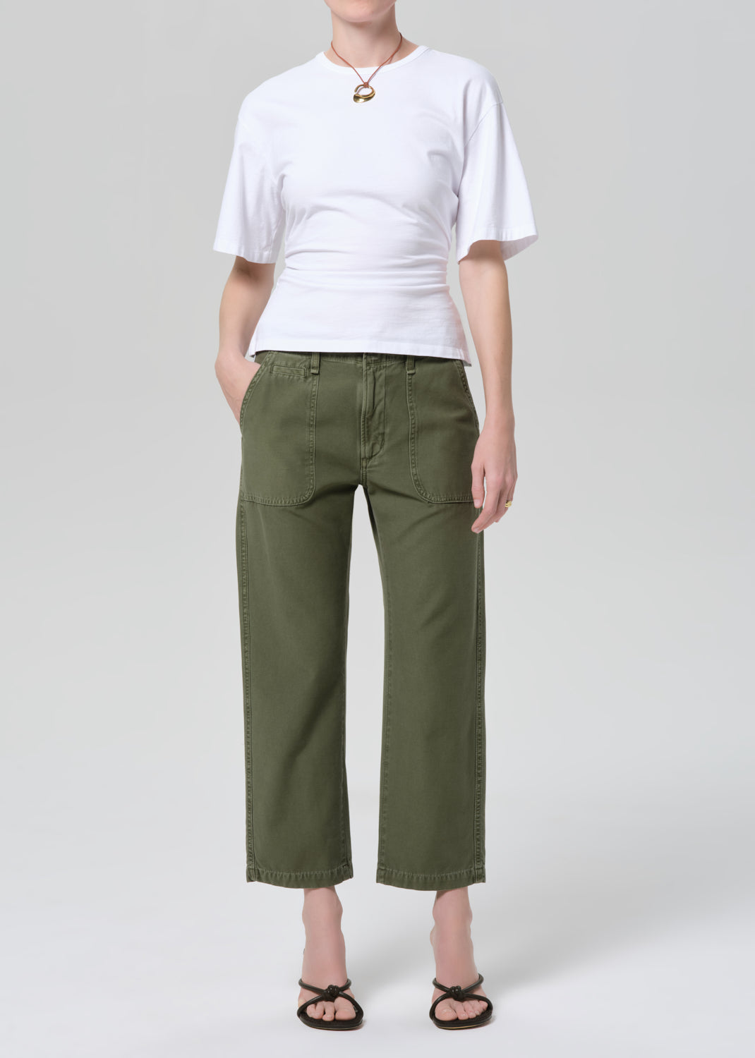 Person wearing a white t-shirt and green pants on a light gray background