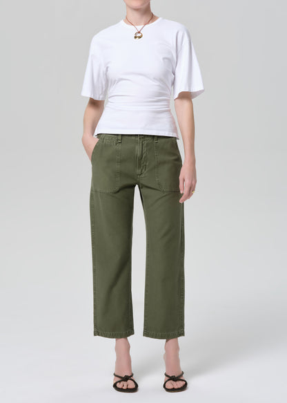Person wearing a white t-shirt and green pants on a light gray background