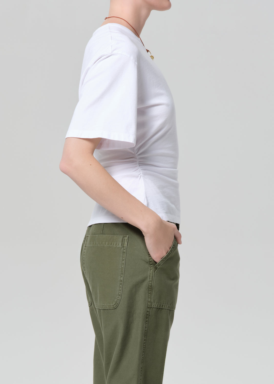 Person wearing a white t-shirt and green pants on a light gray background