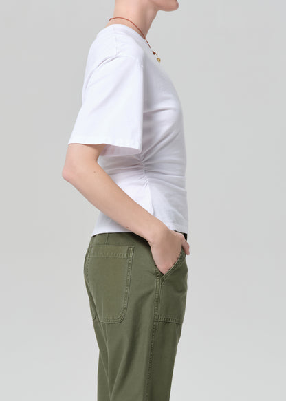 Person wearing a white t-shirt and green pants on a light gray background