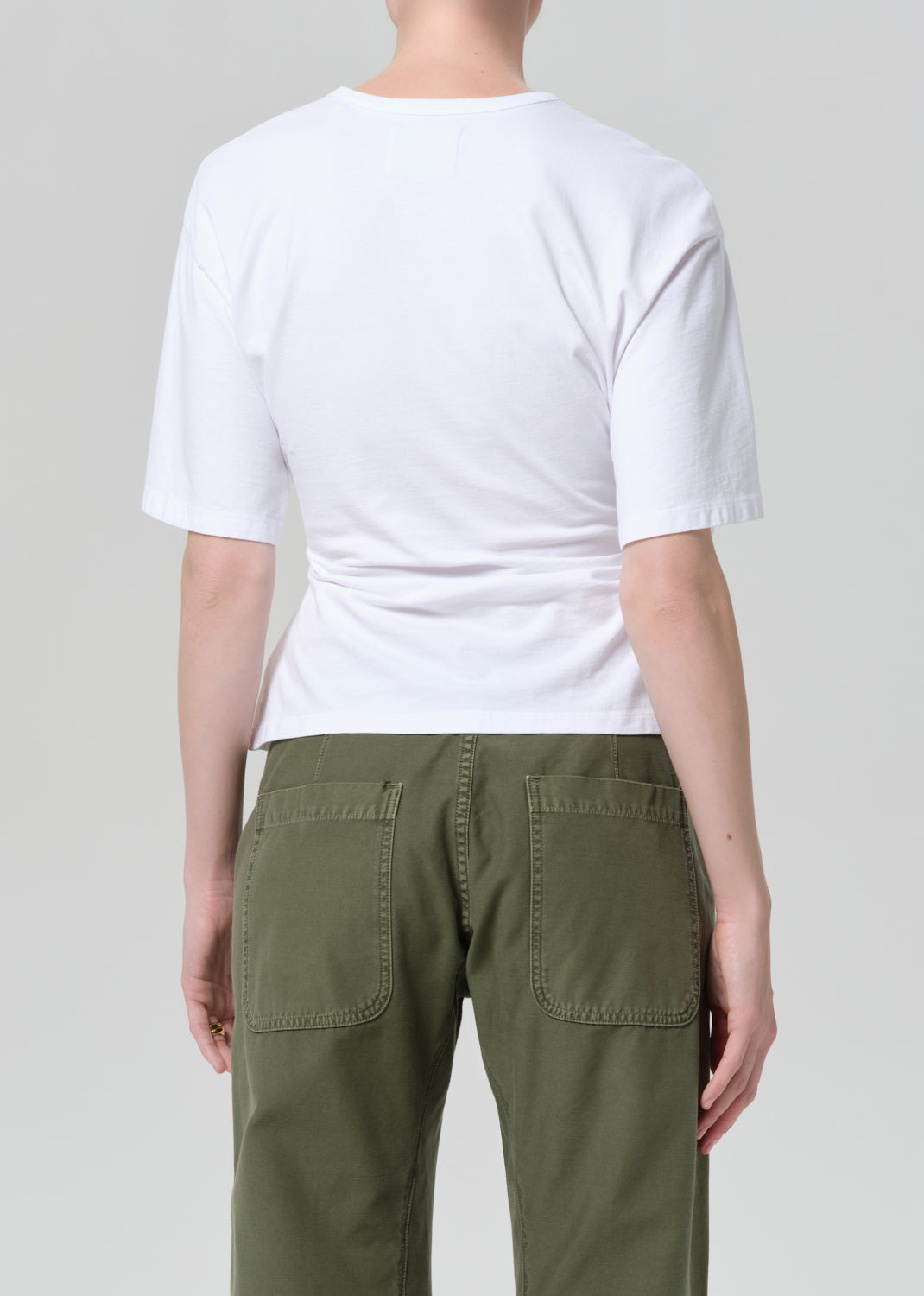 Person wearing a white t-shirt and green pants on a plain background