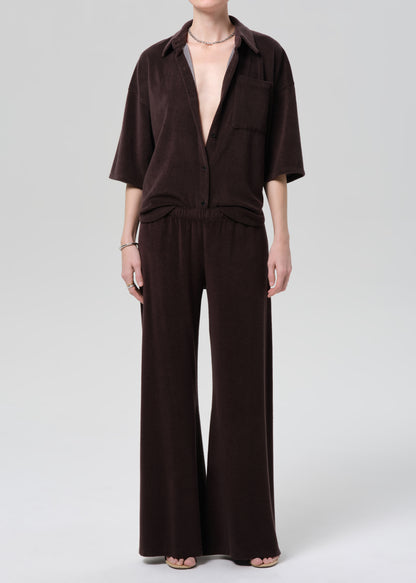 Person wearing a brown terry outfit with a deep neckline on a plain background