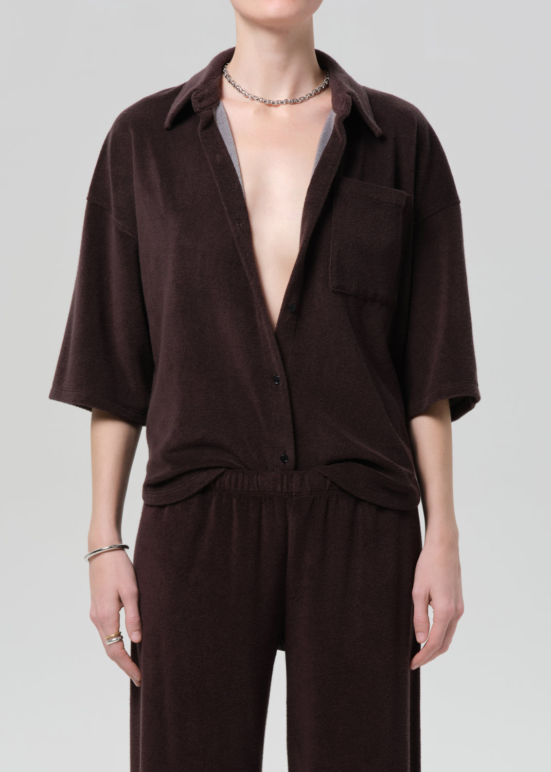 Person wearing a brown terry outfit with a deep neckline on a plain background