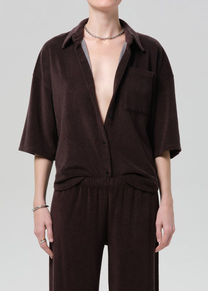 Person wearing a brown terry outfit with a deep neckline on a plain background
