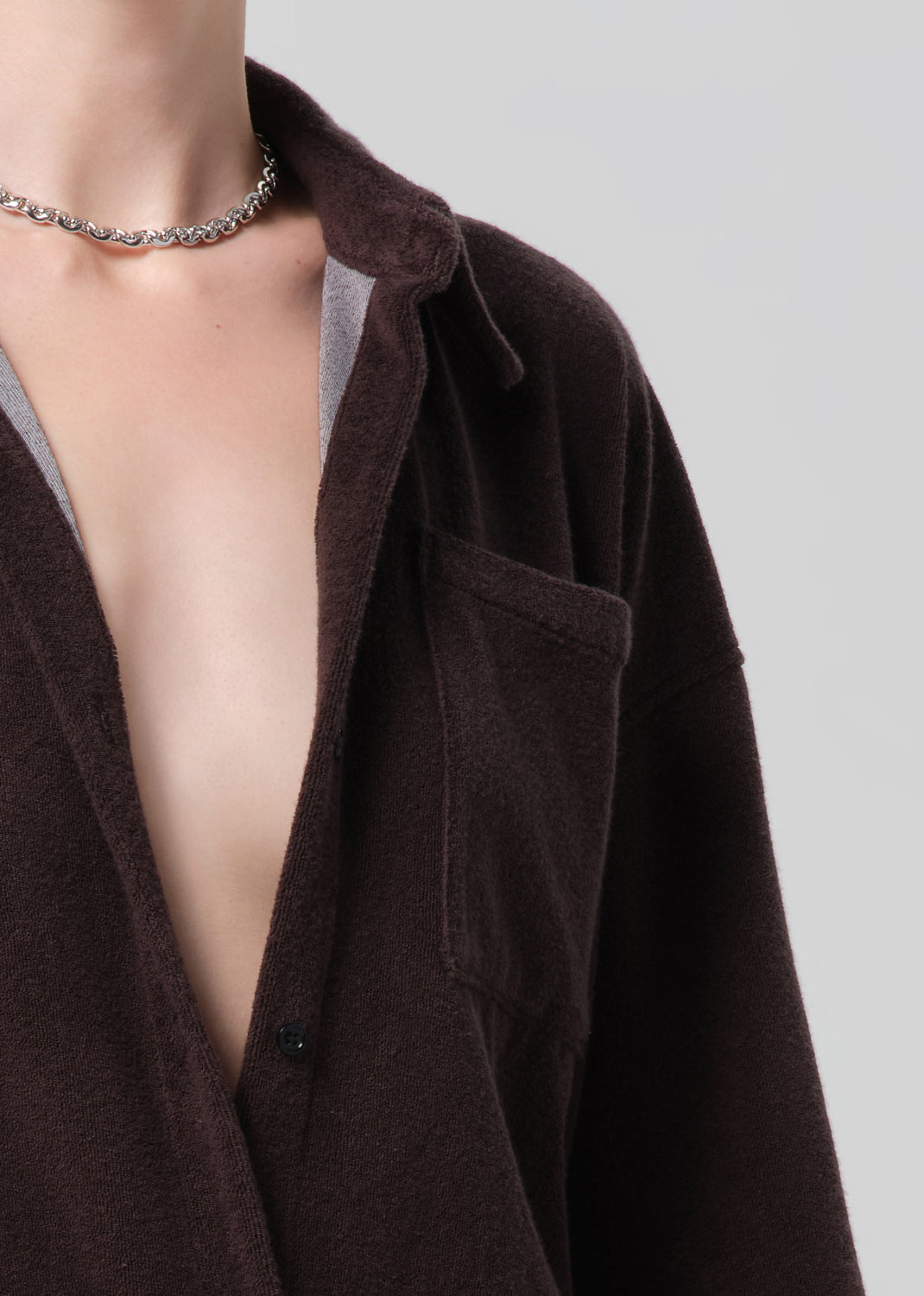 Person wearing a brown terry outfit with a deep neckline on a plain background