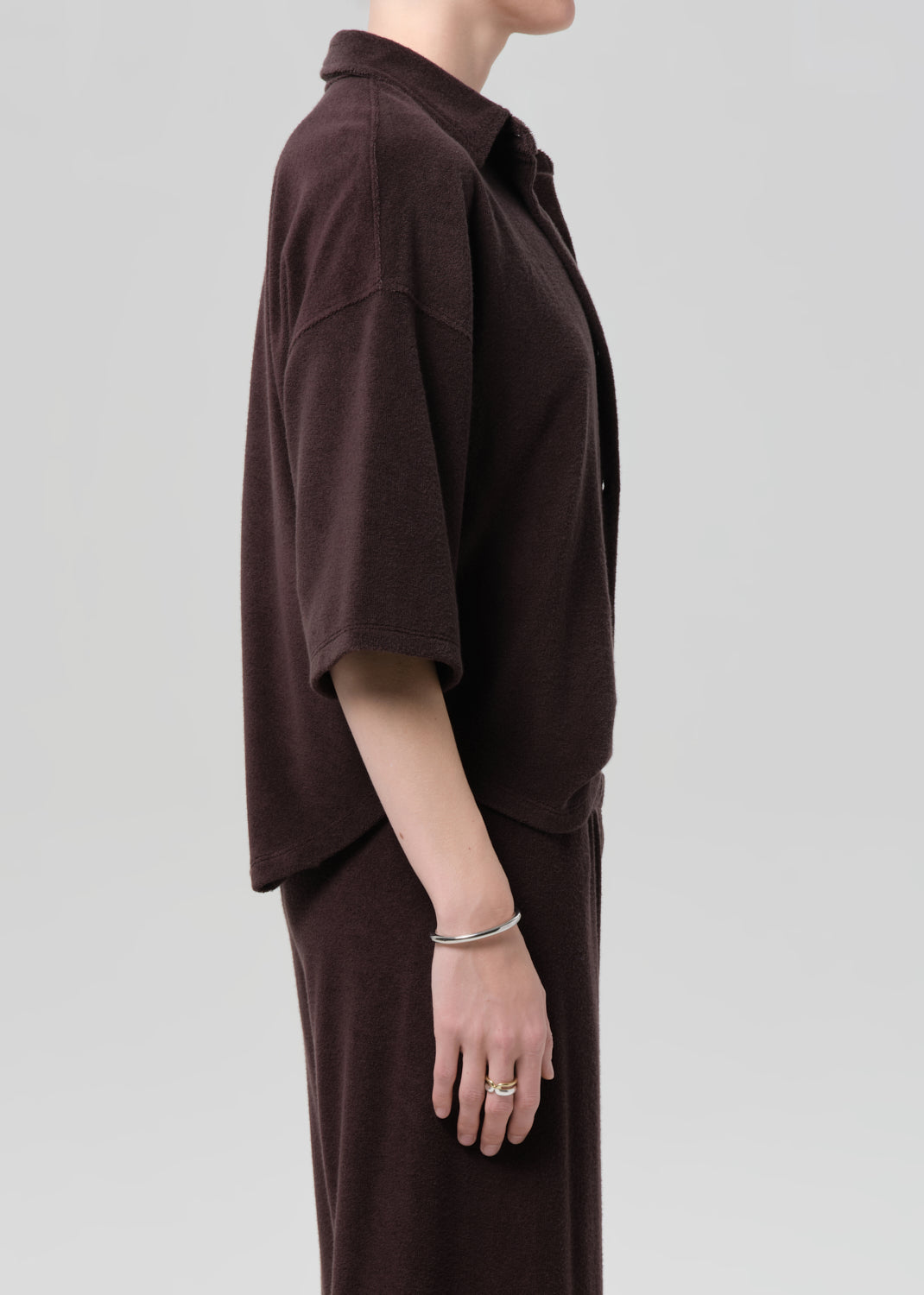 Person wearing a brown terry outfit with a deep neckline on a plain background