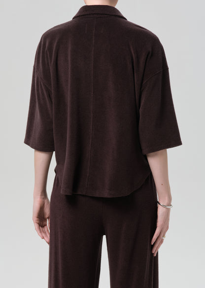 Person wearing a brown terry outfit with a deep neckline on a plain background