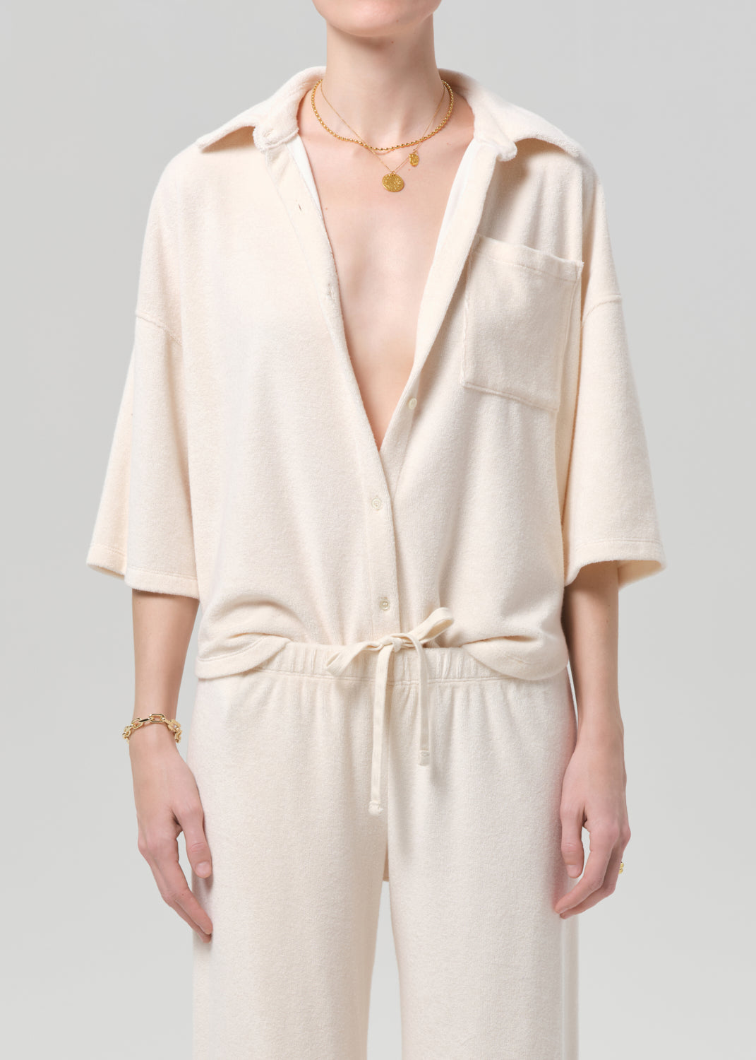 Person wearing a cream-colored terry set with a plain background