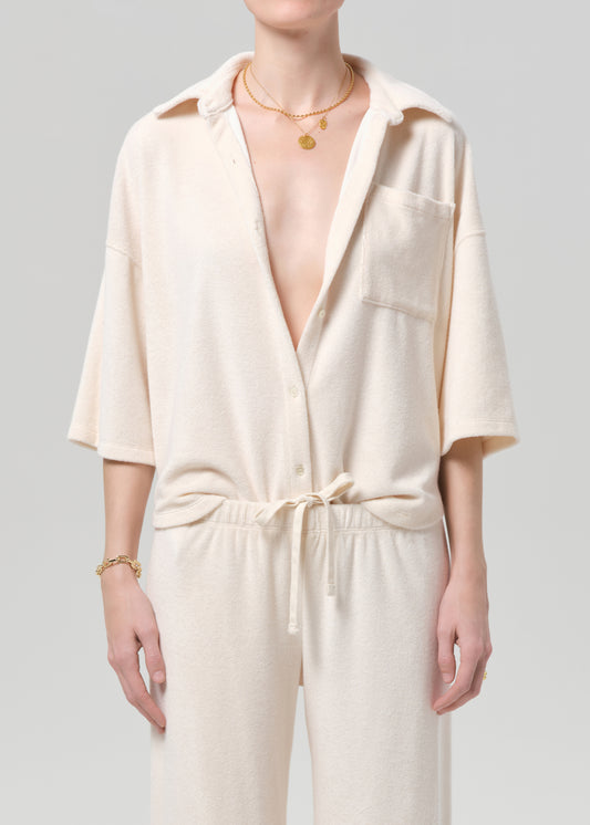 Person wearing a cream-colored terry set with a plain background