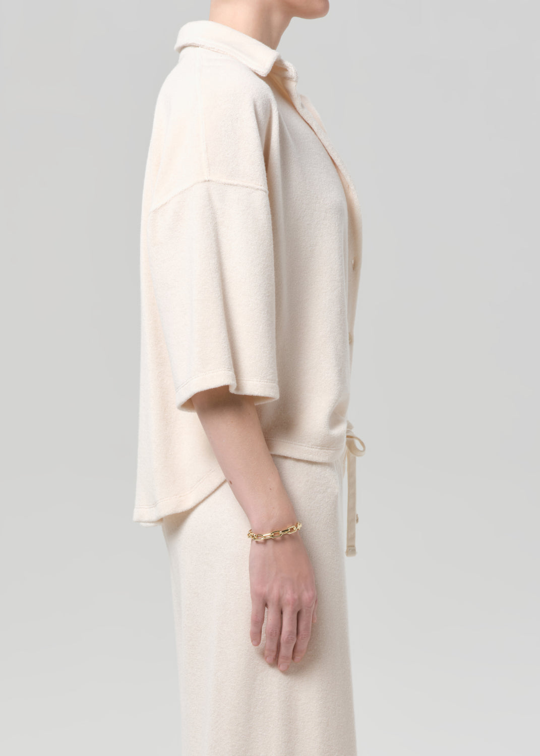 Person wearing a cream-colored terry set with a plain background