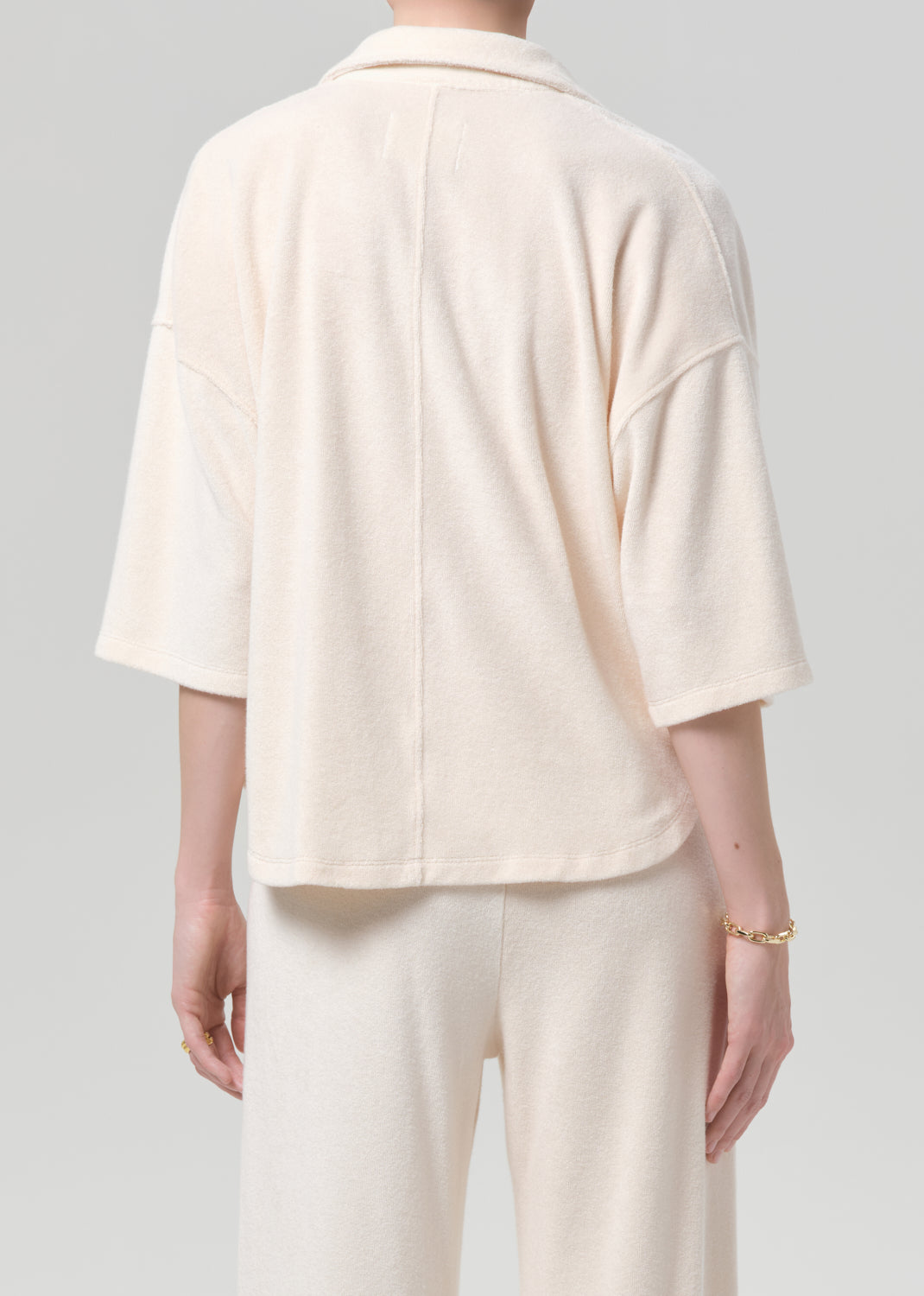 Person wearing a cream-colored terry set with a plain background