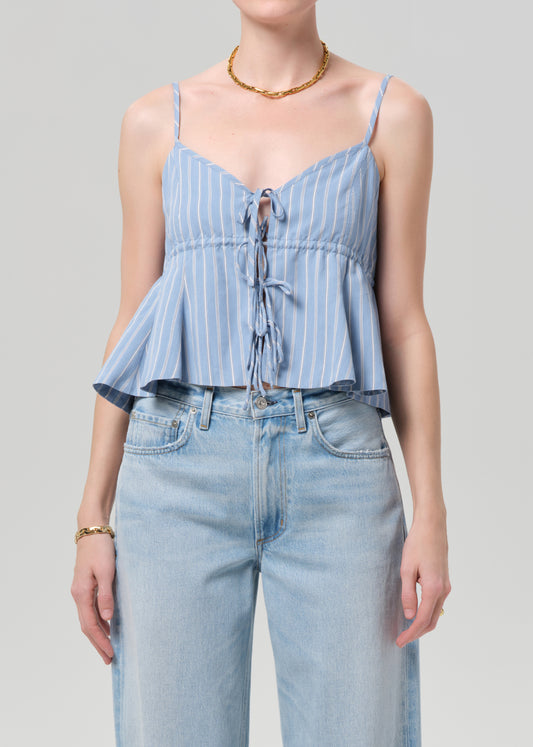 Woman wearing a blue striped top and light blue jeans against a gray background