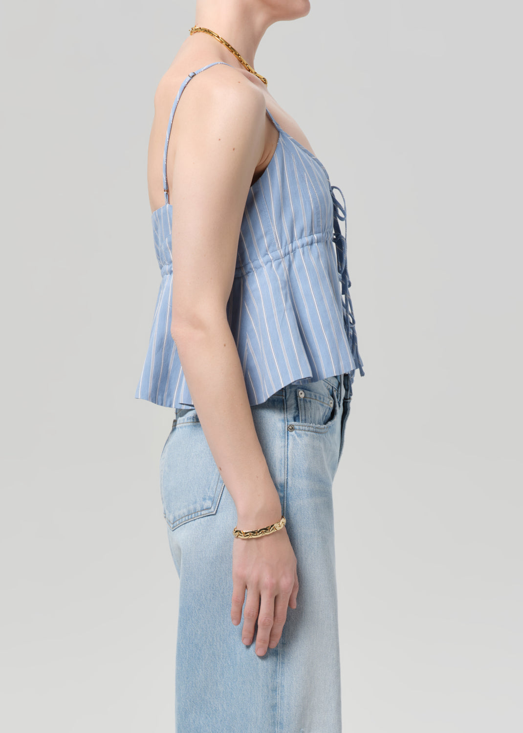 Person wearing a light blue striped top and jeans on a plain background
