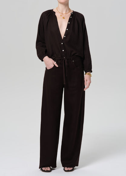 Person wearing a brown linen outfit on a plain background