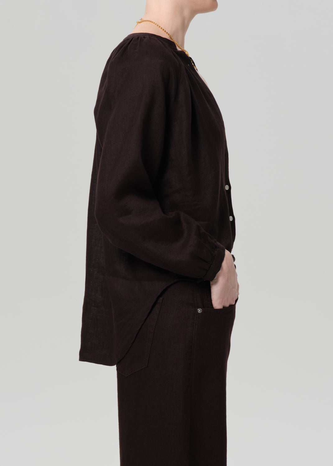 Person wearing a dark brown outfit on a light gray background