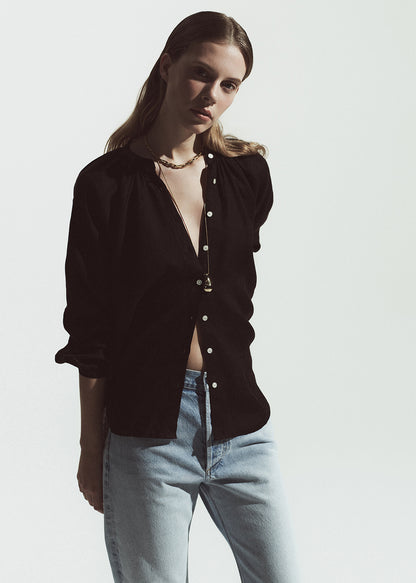 Woman wearing a brown button-up shirt and light blue jeans against a white background