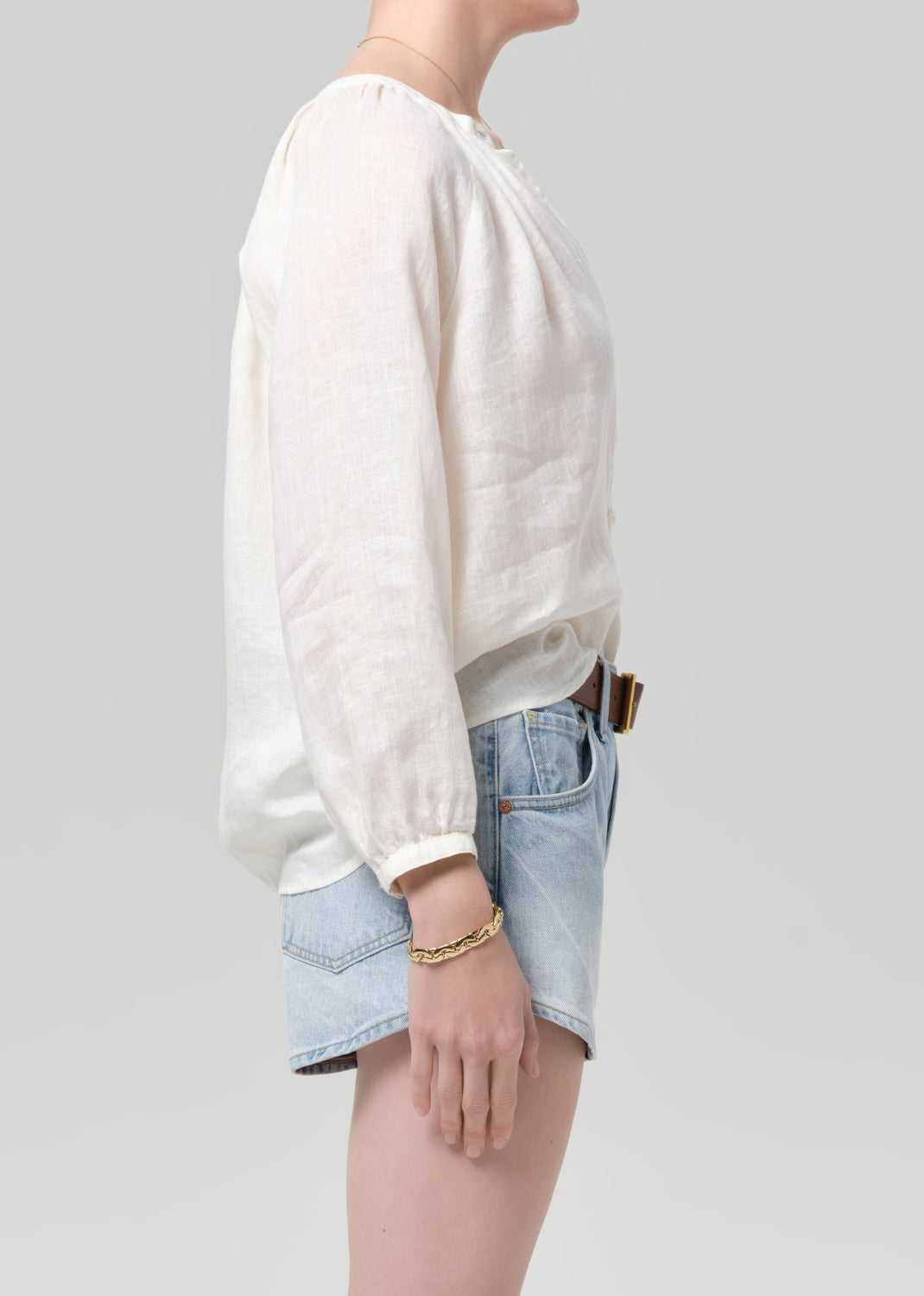 Person wearing a white blouse and denim shorts on a plain background