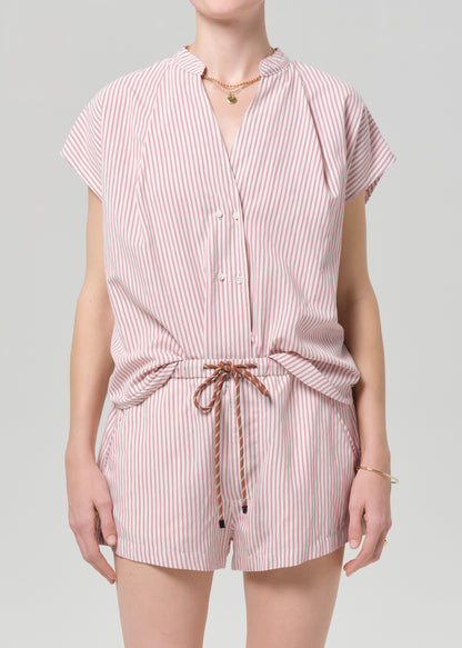 Person wearing a pink and white striped blouse with matching shorts on a gray background