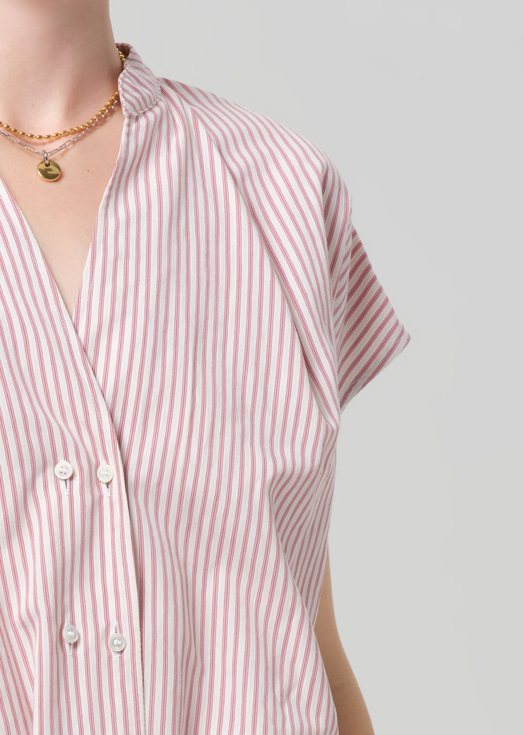 Close-up of a person wearing a pink and white striped shirt against a plain background