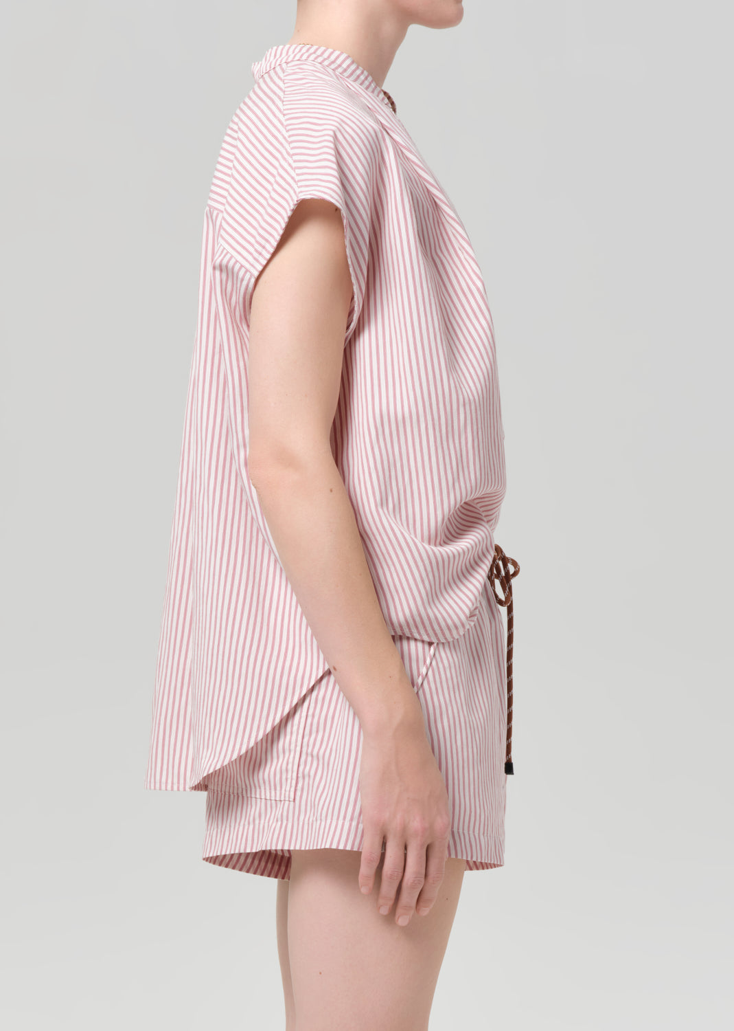Person wearing a pink and white striped blouse with matching shorts on a gray background