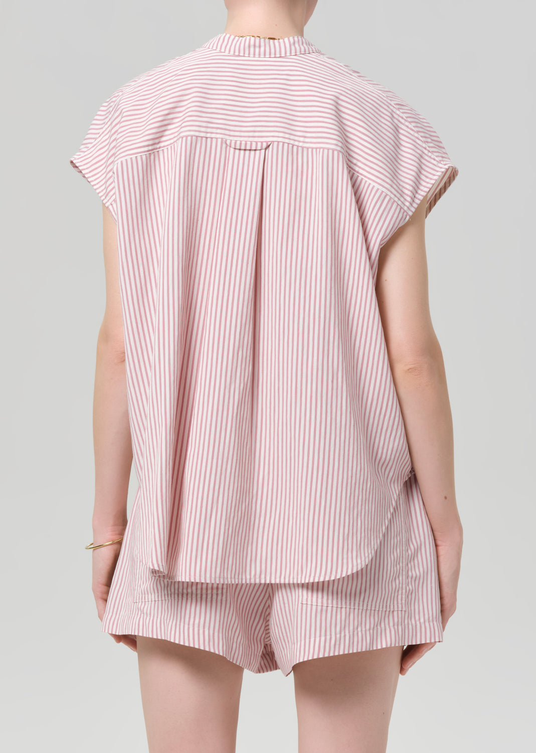 Person wearing a pink and white striped blouse with matching shorts on a gray background