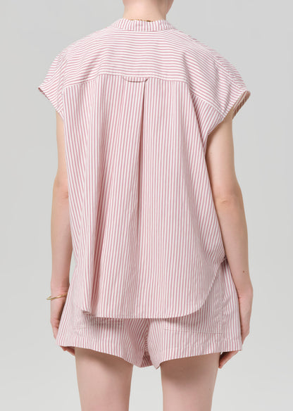 Person wearing a pink and white striped blouse with matching shorts on a gray background