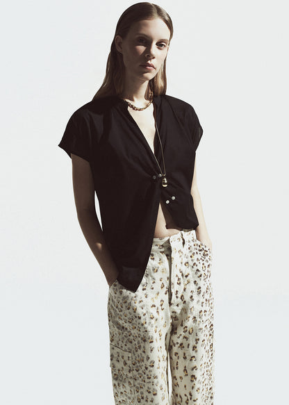 Woman wearing a black top and cheetah pants on a white background