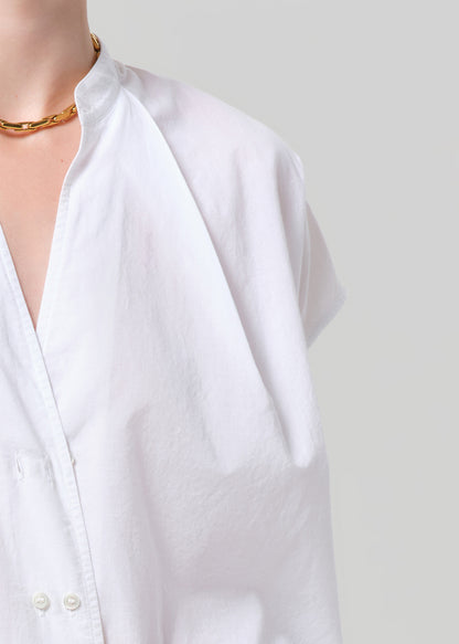 Person wearing a white blouse and pants on a plain background