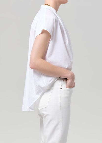 Person wearing a white blouse and pants on a plain background