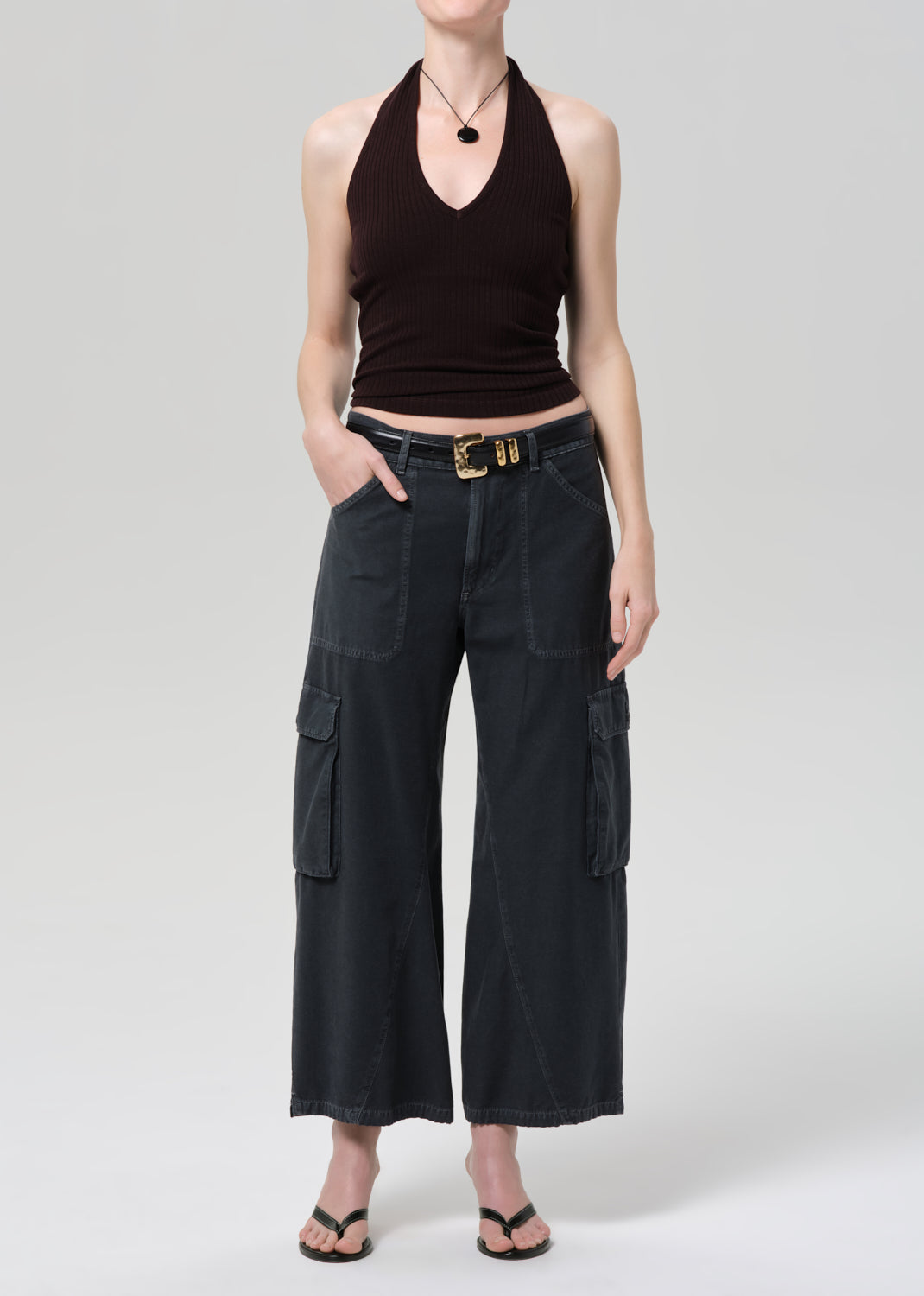 Person wearing a brown halter top and wide-leg cargo pants on a plain background