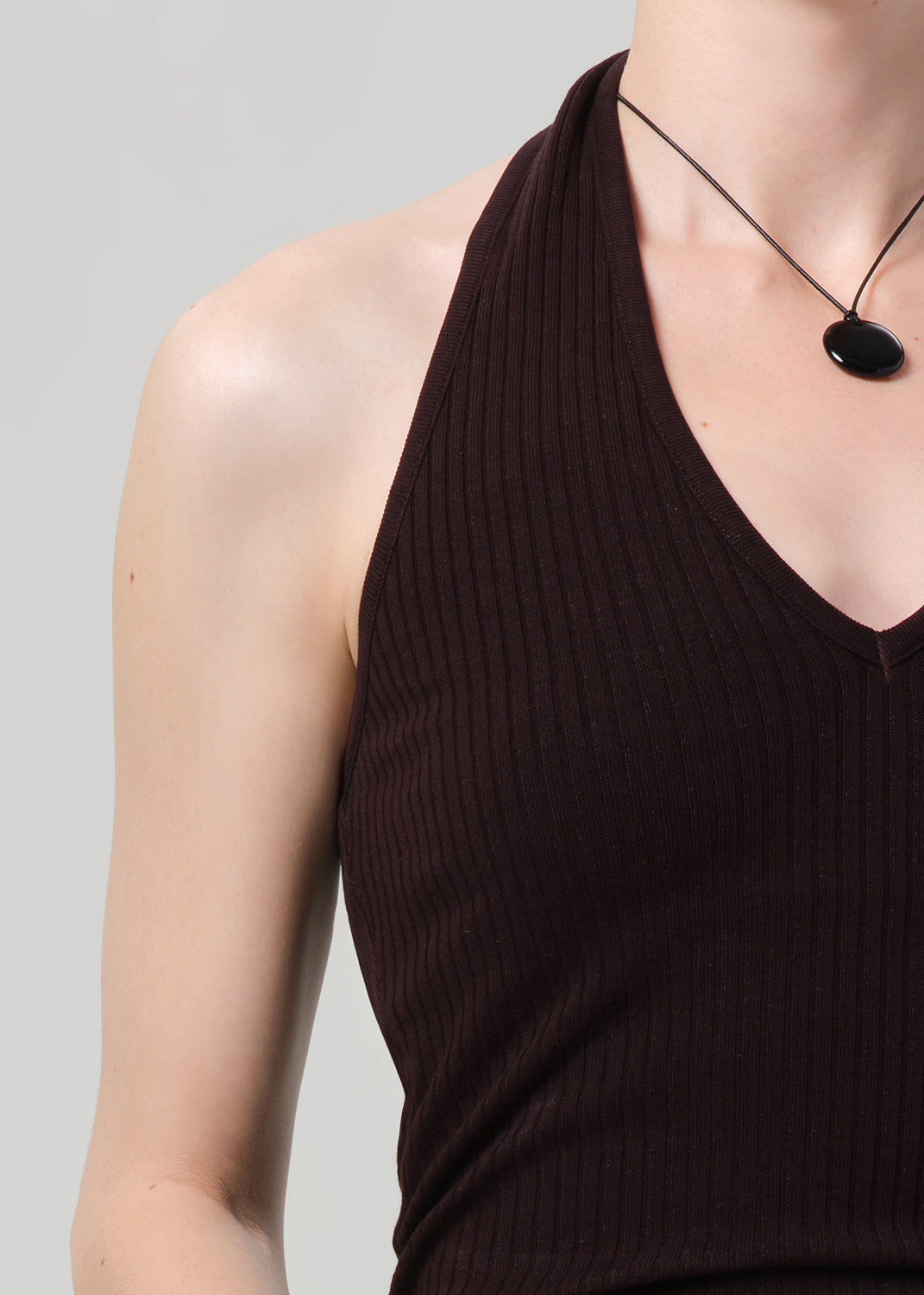Person wearing a brown halter neck top against a gray background