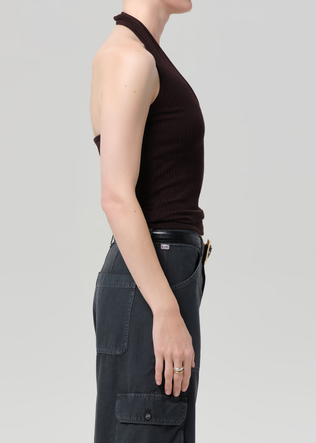 Person wearing a brown halter top and dark cargo pants on a light gray background