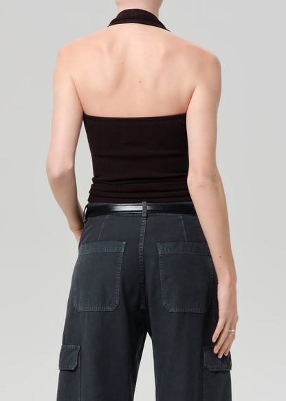 Person wearing a brown halter top and dark cargo pants on a plain background