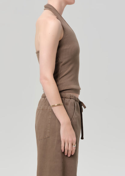 Person wearing a brown sleeveless top and pants on a light gray background