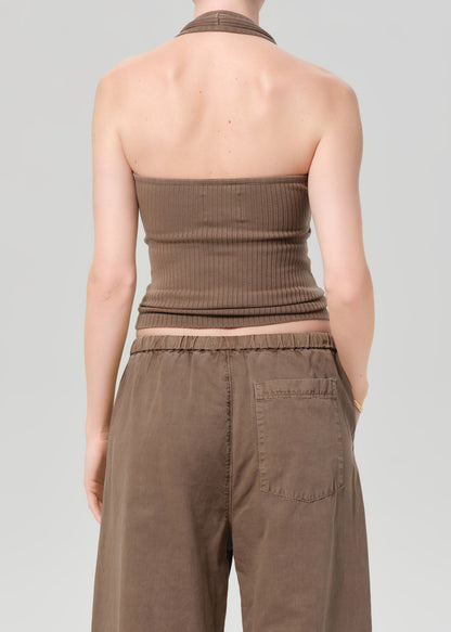 Person wearing a brown strapless top and pants on a gray background