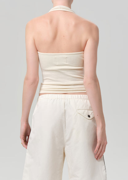 Person wearing a cream halter top and white shorts on a light gray background