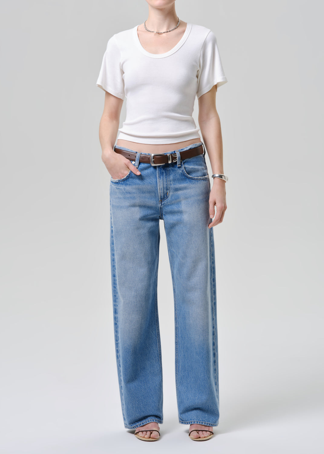 Person wearing a white tee and blue jeans on a plain background