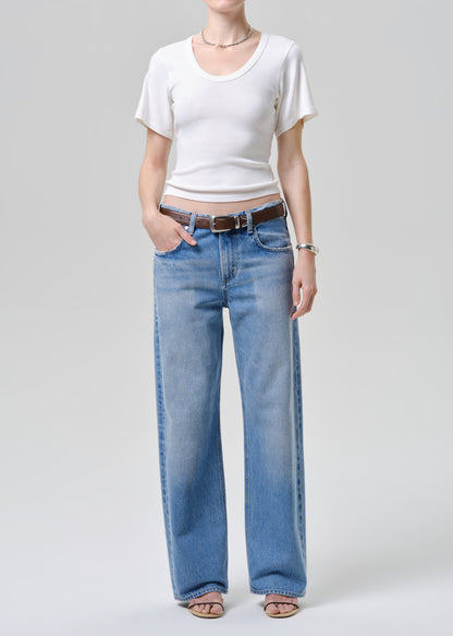 Person wearing a white tee and blue jeans on a plain background