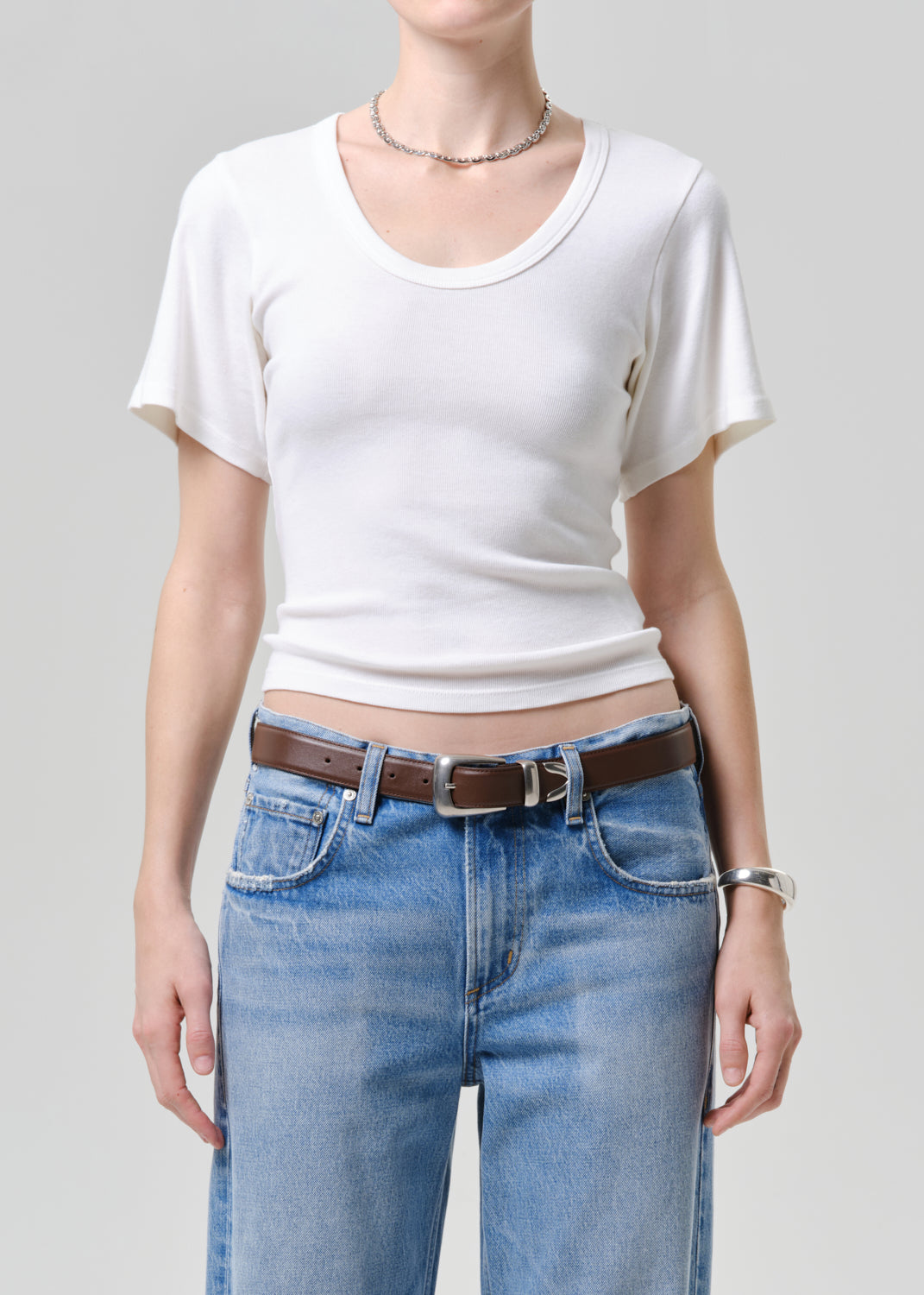 Person wearing a white tee and blue jeans on a plain background
