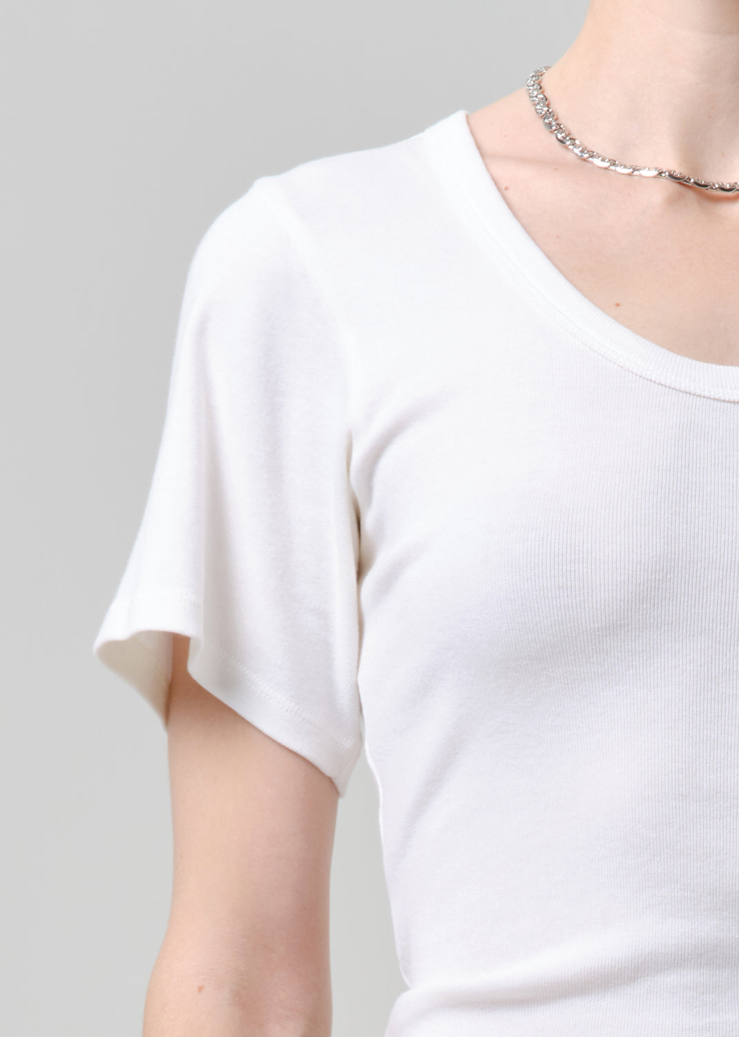Person wearing a white tee and blue jeans on a plain background