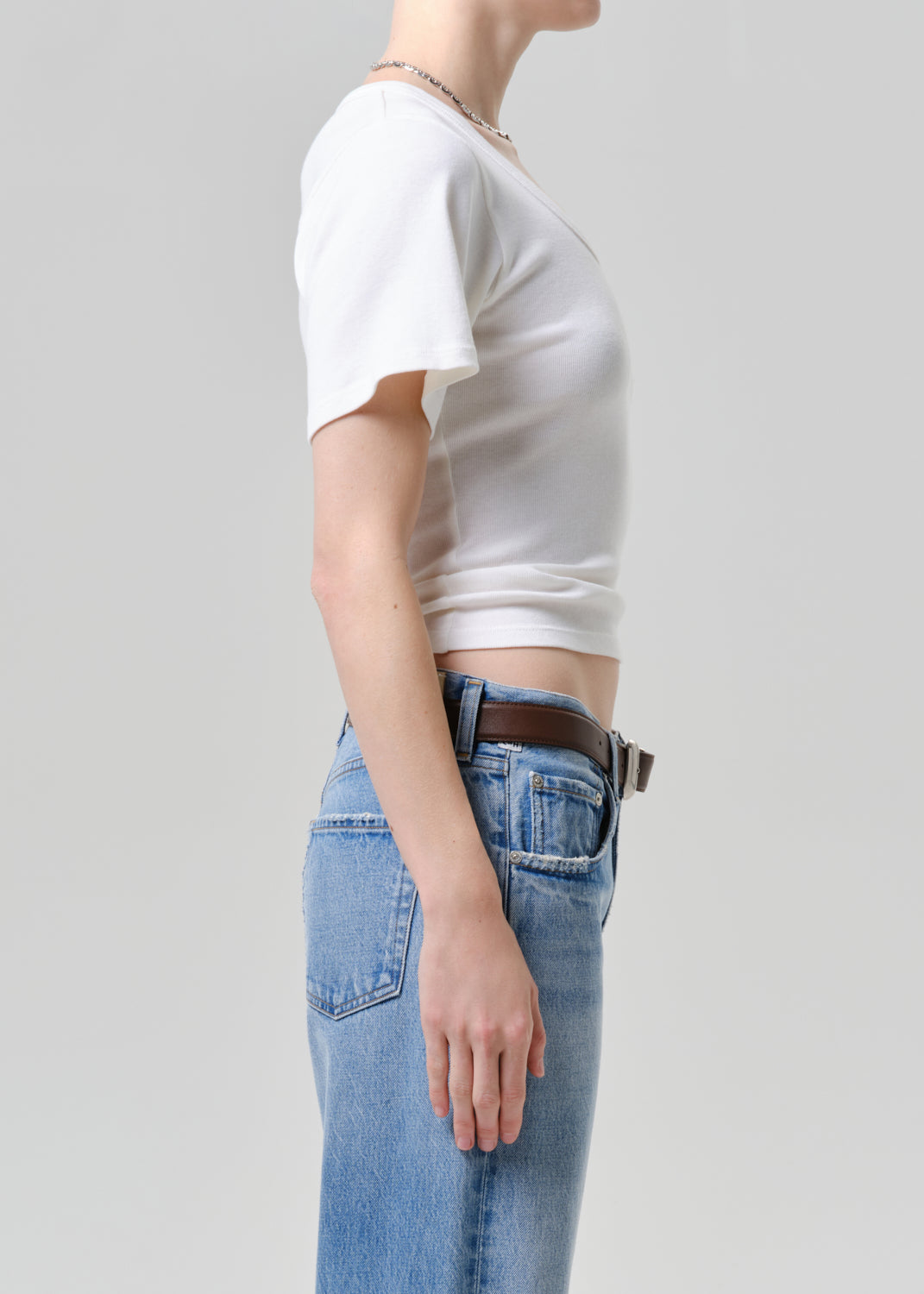 Person wearing a white tee and blue jeans on a plain background