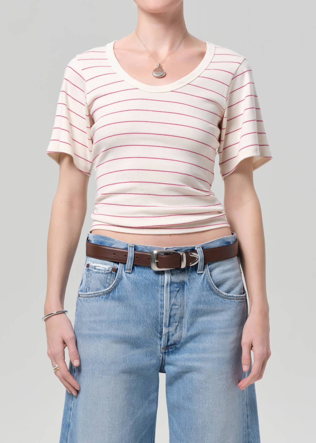 Person wearing a striped shirt and jeans on a plain background