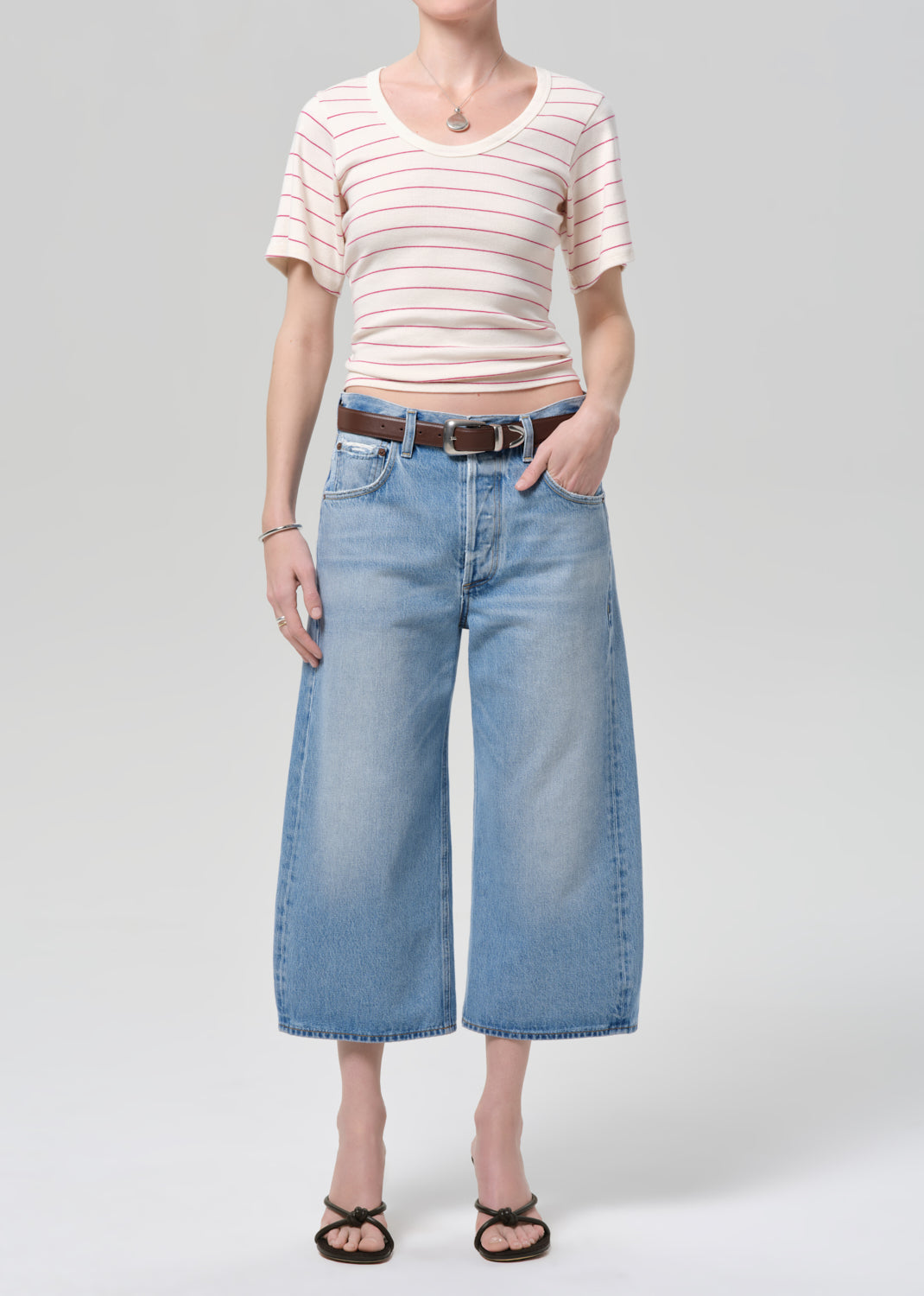 Person wearing a striped shirt and wide-leg jeans on a plain background