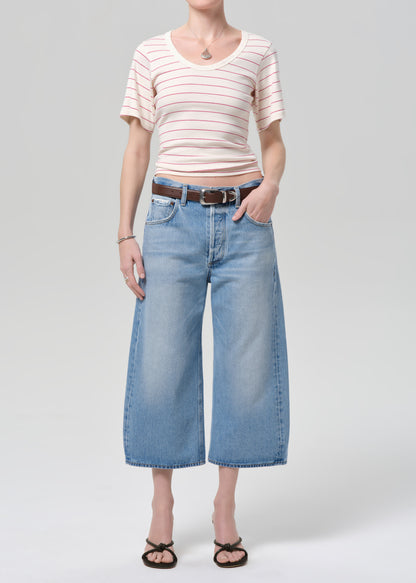 Person wearing a striped shirt and wide-leg jeans on a plain background