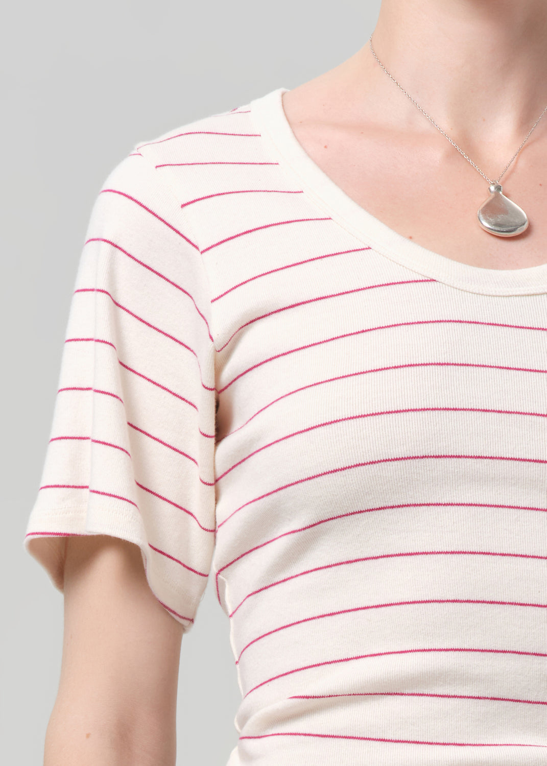 White t-shirt with red stripes worn by a person on a gray background