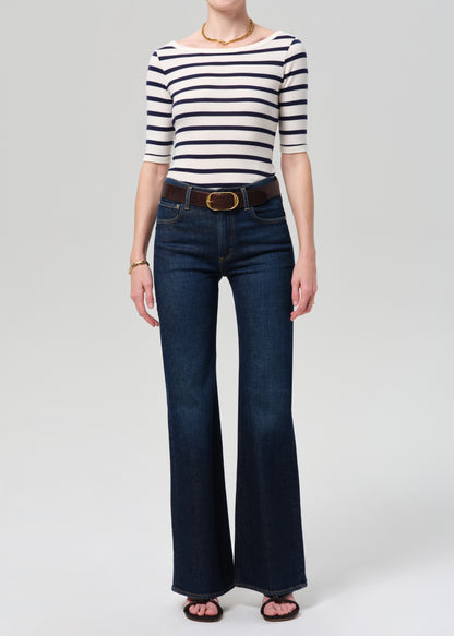 Person wearing a striped shirt and blue jeans on a grey background